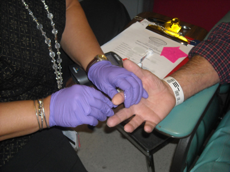 MRI tech doing a fingerstick on a patient in JHOC